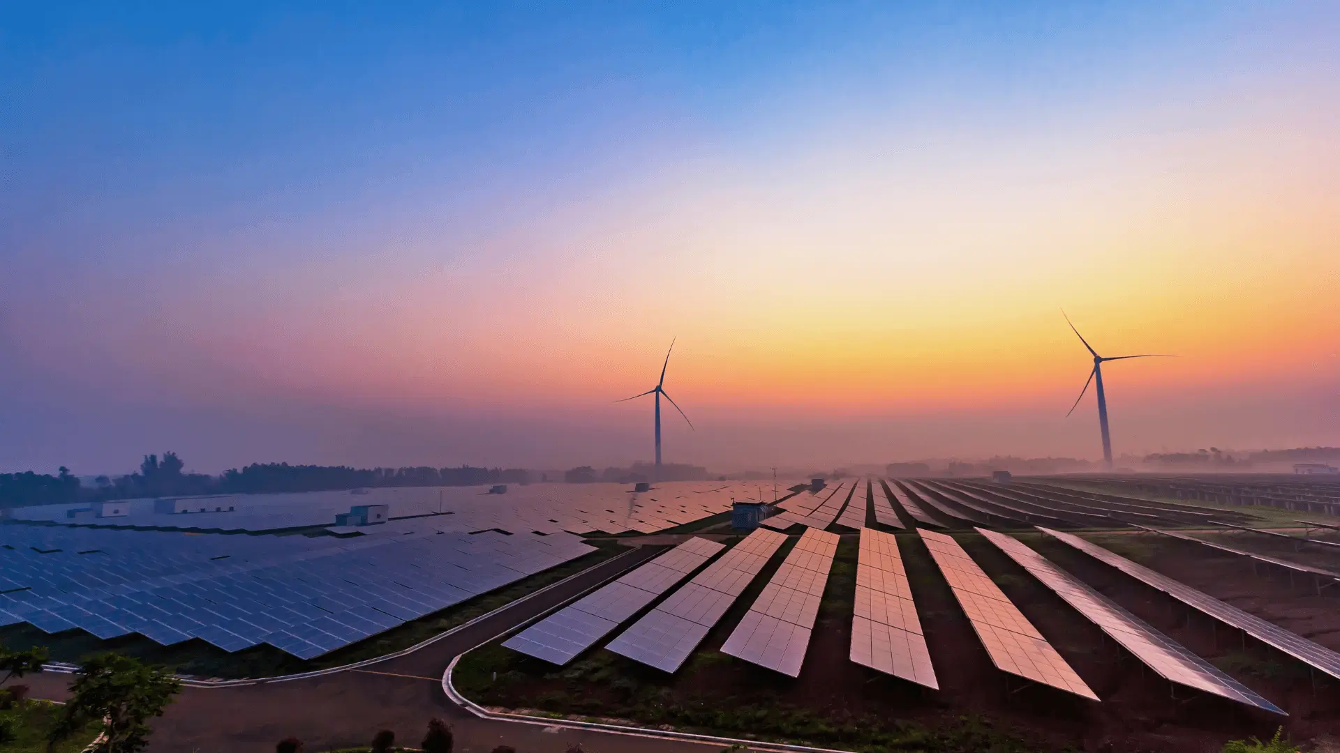 Wide view of solar arrays and wind turbines at dusk